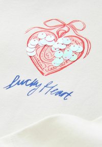 Bawełniany t-shirt z czerwonym sercem ozdobionym połyskującymi cekinami oraz napisem „Lucky Heart” w niebieskim kursywie.