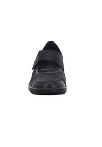 Schwarzer Schuh mit Obermaterial aus Stoff und Klettverschluss. Runde Zehenpartie, gepolsterte Innensohle und schwarze Gummisohle. Subtile Texturierung des Obermaterials.