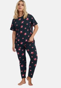 Set di pigiama in cotone nero con motivi a stella rosa oversize; top a maniche corte e pantaloni aderenti con vita elastica. Tessuto morbido.