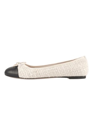 Chaussure plate en tissu texturé crème avec embout arrondi noir et petit nœud décoratif près des orteils sur fond blanc.