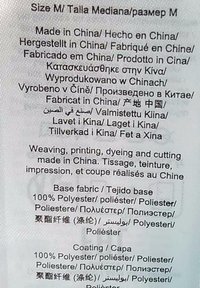 Label met meertalige zorginstructies, voornamelijk in zwarte tekst op een lichte stoffen achtergrond, die de materiaal samenstelling en oorsprong beschrijft.