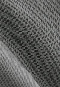 Tekstil med en fin rutenetstruktur i nuancer af grå, der viser en glat finish og let glans. Materialet fremstår blødt og fleksibelt.