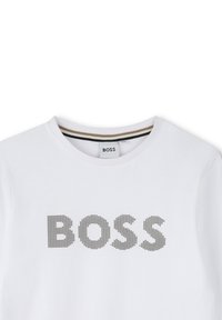 Witte crewneck t-shirt met zwart gestippelde tekst "BOSS" gecentreerd op de borst en een label in de kraag met dezelfde merknaam.