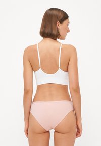 White ribbed bralette with adjustable straps and a pink brief. Soft fabric with a smooth texture, featuring minimalistic design and no patterns.