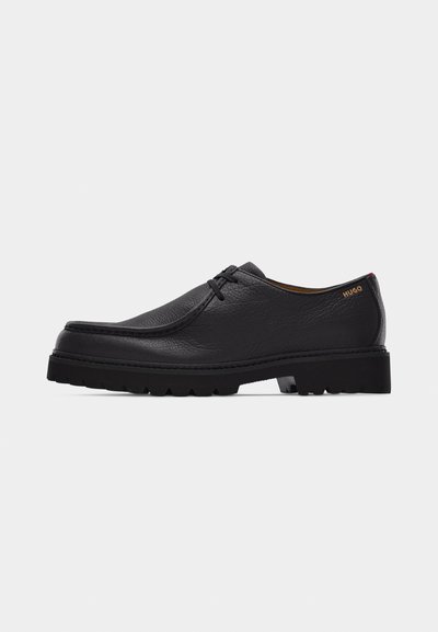 Chaussure habillée noire en cuir à lacets avec semelle épaisse en caoutchouc et logo "HUGO" sur le talon, présentée de profil sur un fond blanc.