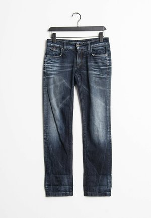 Mørkeblå, falmede, lige bukser hængende på en sort bøjle mod en hvid baggrund.