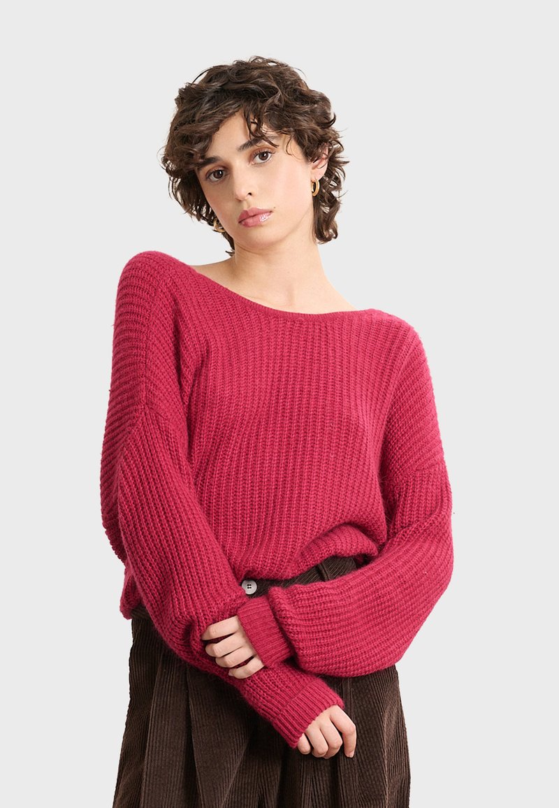 Wollpullover in tiefem Rosa, mit lockerer Passform, weitem Ausschnitt und geripptem Muster. Lange Ärmel mit verlängerten Bündchen.