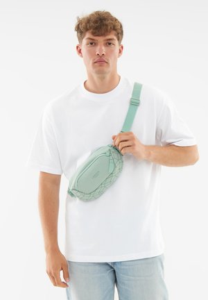 Light mint green crossbody bag with geometric pattern, made of soft material. Features adjustable strap and zip closure.