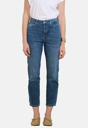 Modre kavbojke z visokim pasom, prilegajoče se bokom z rahlim zašiljenjem. Iz džinsa z minimalnim bledenjem, z zasnovo s petimi žepi in zankami za pas.