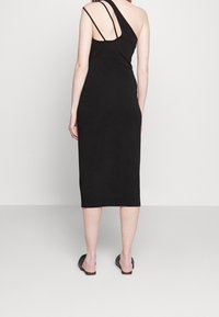 Robe noire ajustée midi avec un design d'épaule asymétrique et des fines bretelles. Texture lisse sans motifs ni accents visibles.
