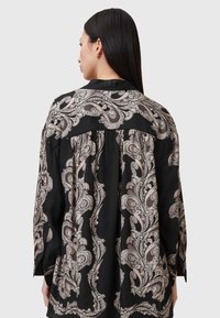 Blusa nera a maniche lunghe con motivo paisley in beige e grigio. Tessuto morbido con vestibilità ampia e dettaglio con piega sul retro.