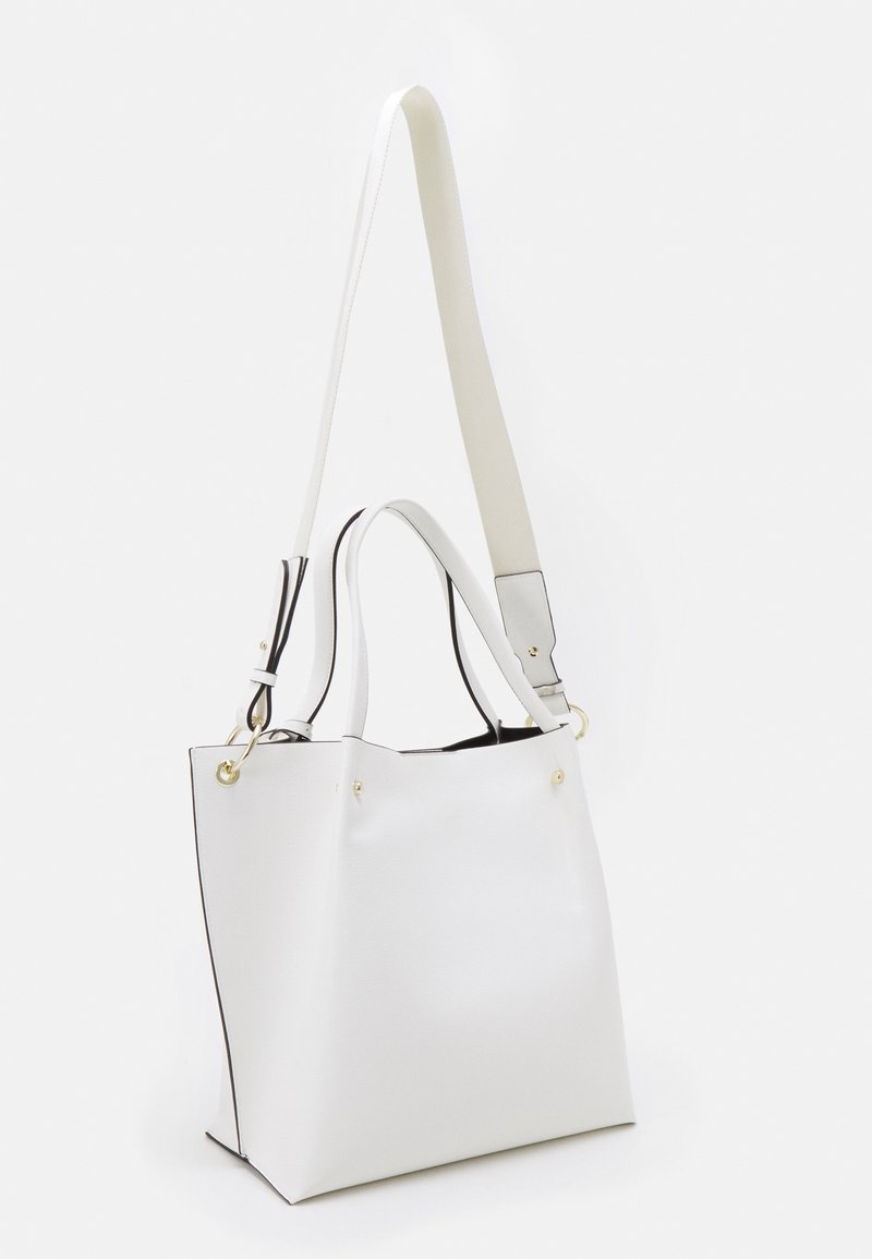 Bílá syntetická taška přes rameno se strukturovaným tvarem, s černým olemováním, odnímatelným popruhem a zlatými akcenty. Texturovaný povrch.