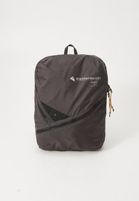 Schwarzer Nylon-Rucksack mit schlanker Form, diagonalem Reißverschluss, Netzelementen und einem Tragegriff oben. Markenname und Modell sichtbar.
