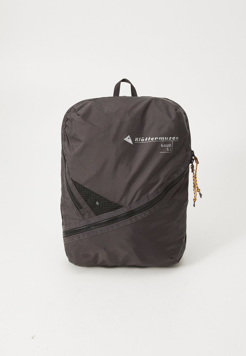 Schwarzer Nylon-Rucksack mit schlanker Form, diagonalem Reißverschluss, Netzelementen und einem Tragegriff oben. Markenname und Modell sichtbar.