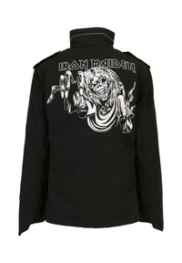 Juodas švarkas su dideliu baltu grafiniu vaizdu, vaizduojančiu padarą su ilgais plaukais ir naginiais rankomis, virš dizaino yra tekstas "IRON MAIDEN".