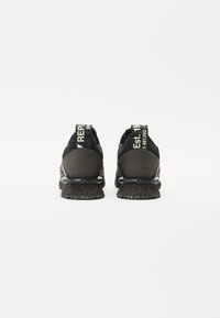 Schwarze Sportschuhe mit einer strukturierten schwarzen Sohle, versehen mit einer grünen Zuglasche, die auf der Rückseite den Text "REP." und "Est. 19" für zusätzliche Details aufweist.