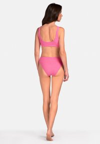Różowy dwuczęściowy kostium kąpielowy z teksturowanym wzorem; crop top ma szerokie ramiączka, a dół o wysokim stanie ma umiarkowane wycięcie, gładkie wykończenie materiału.