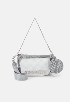 Mała biała i srebrna torebka z odpinanym łańcuszkiem i paskiem, wyposażona w okrągłą, teksturowaną sakiewkę na monety oraz srebrne logo "Steve Madden" z przodu.