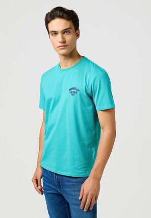 Turkoois katoenen t-shirt met korte mouwen, ronde halslijn en een lichte pasvorm. Bevat een klein marineblauw logo op de borst.