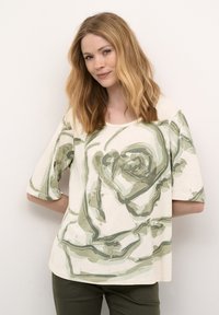 Top de manga corta color crema con un estampado de rosa oversized en tonos verdes. El tejido tiene una textura suave y relajada.