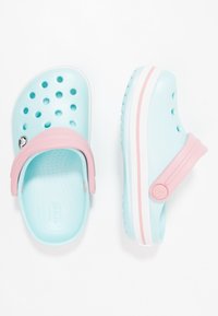Aqua blue and pink plastic clogs with ventilation holes, an adjustable heel strap, and a white sole featuring pink accents.