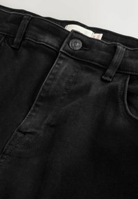 Black denim jeans with a button closure, five-pocket design, and visible stitching details. Smooth texture and tailored fit.