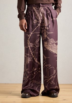 Wide-leg pants in dark maroon fabric featuring a contrasting gold map print. Smooth texture with pleated details and side pockets.