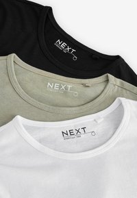 Trzy t-shirty z okrągłym dekoltem w kolorze czarnym, oliwkowym i białym. Miękka bawełniana tkanina z metką marki „NEXT” na dekolcie każdej koszulki.