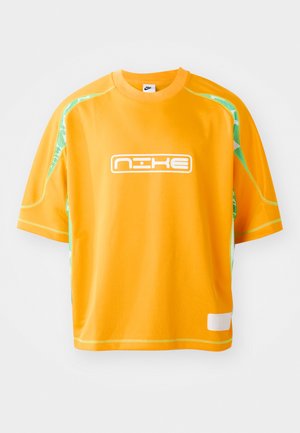 Orange sports t-shirt made from lightweight fabric, featuring a white Nike logo, green mesh accents on the shoulders, and a boxy fit.