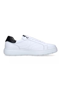 Zapatilla blanca de corte bajo con talón negro, cordones blancos y suela gruesa vista de lado sobre un fondo blanco.