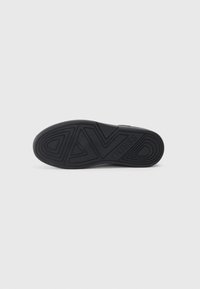 Suela de zapato de goma negra con patrón de relieve geométrico y logo en relieve. Diseño plano, textura suave y material duradero.
