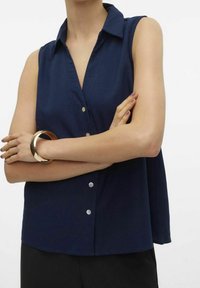 Mörkblå ärmlös skjorta med krage, med en knappslutning framtill och en avslappnad passform. Mjuk tyg och subtil glans.