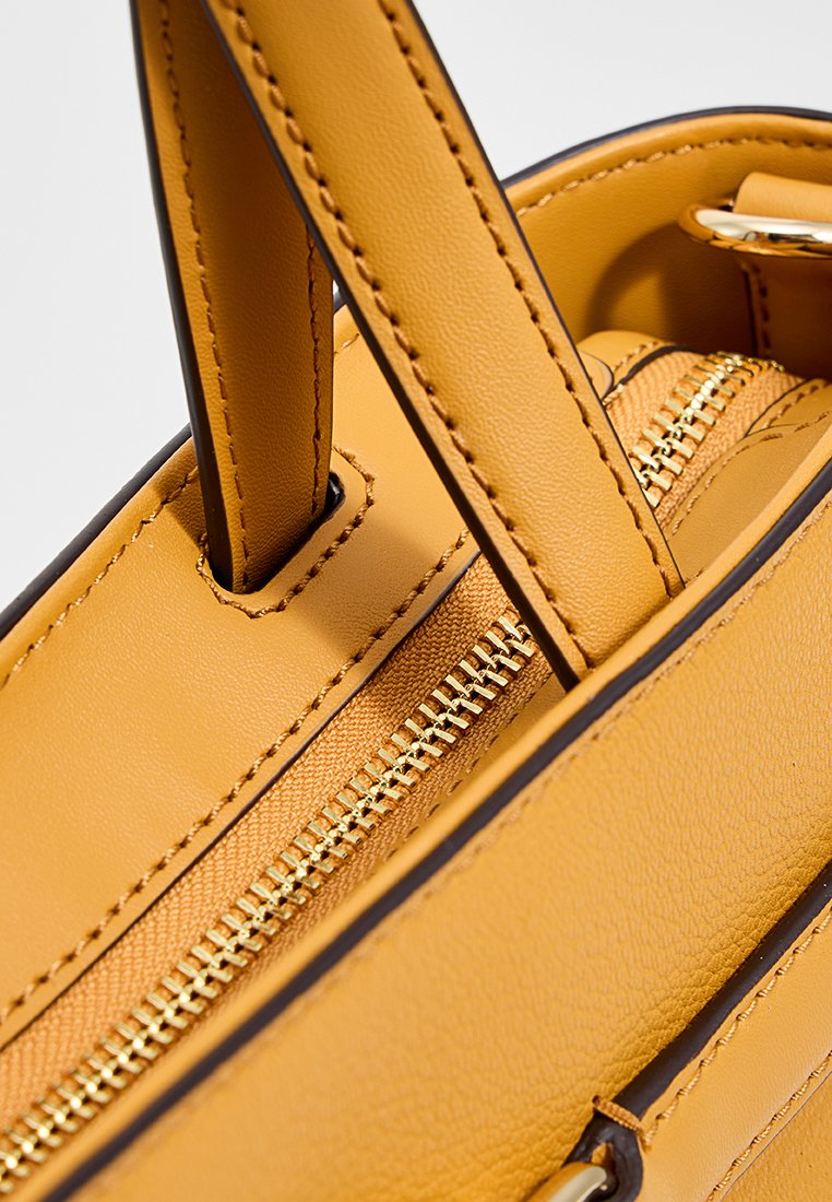 Sac à épaule en cuir jaune avec doubles poignées supérieures, compartiment principal zippé avec fermeture éclair dorée et finition sombre contrastante.