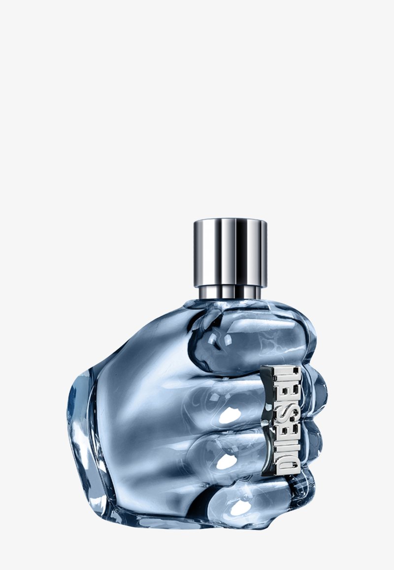 Transparent blå glasflaska formad som en knuten hand, med en silverkapsyl och en framträdande silveretikett med "Diesel" på sidan.