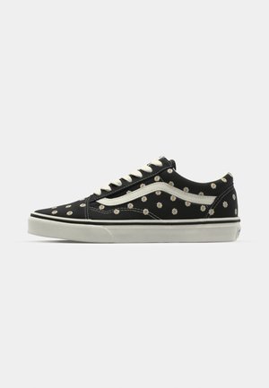 Sneakers in tela nera con motivi di margherite bianche, con una striscia laterale in pelle bianca, lacci crema e suola in gomma. Design low-top classico.