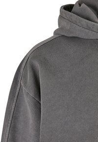 Felpa grigia con cappuccio caratterizzata da una texture morbida, tessuto a costine e una vestibilità rilassata con un cappuccio prominente e cuciture sulle spalle.