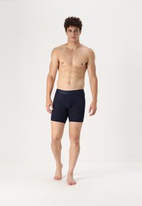 Marineblaue Boxershorts aus weichem Stoff mit konturiertem Beutel, mit einem Logo am Bund und einem glatten, figurbetonten Design.