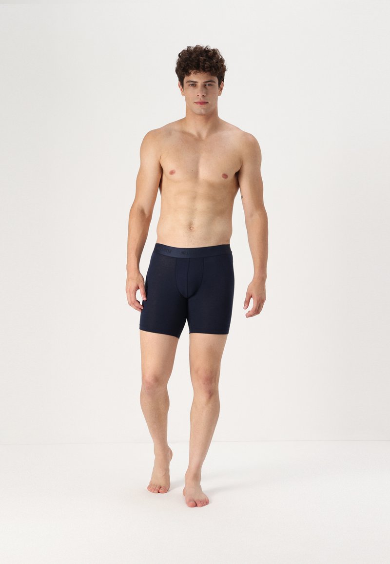 Marineblaue Boxershorts aus weichem Stoff mit konturiertem Beutel, mit einem Logo am Bund und einem glatten, figurbetonten Design.