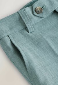 Shorts en lin teal clair avec un tissu texturé, présentant une fermeture à boutons et un design à l'avant plat. Détails de couture le long des jambes.