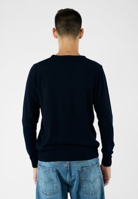 Maglione lavorato a maglia blu navy con scollatura rotonda e maniche lunghe. Texture liscia, aderente in vita, design semplice, adatto per essere indossato a strati.