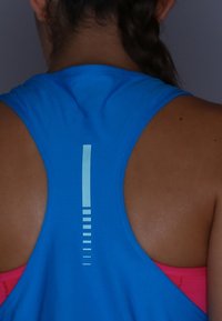 Modrý atletický top s designem racerback, který má vertikální světle modrý pruh a horizontální akcenty na zádech.