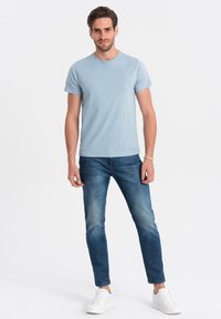 Lyseblå bomulds T-shirt med rund hals, parret med mørkeblå slim-fit jeans og hvide sneakers. Simpel, afslappet stil.