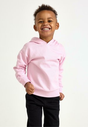 Rosa bomullshoodie med V-formad ringning och ribbade muddar, bärs med svarta byxor. Barnet har kort lockigt hår och ler.