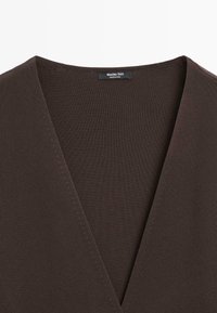 Donkerbruine diep V-hals gebreide top met zichtbare stiknaden en een klein zwart Massimo Dutti-label aan de binnenkant van de kraag.