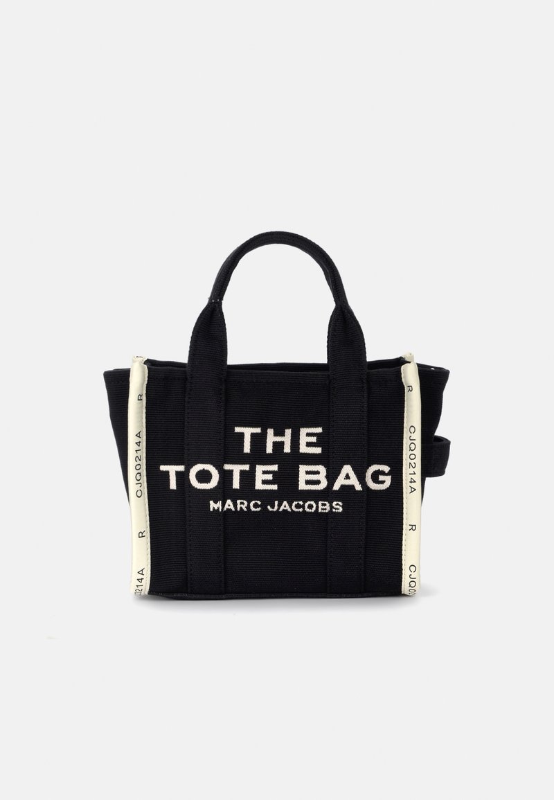 Saco tote preto da Marc Jacobs com riscas verticais brancas nas laterais e texto em branco em destaque "THE TOTE BAG MARC JACOBS" na frente.