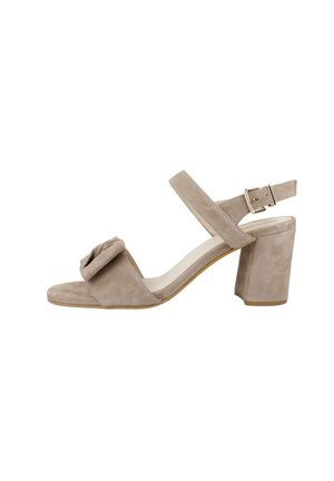 Sandalias de ante beige con tacón, punta cuadrada, tira en el tobillo y detalle de lazo decorativo en la parte delantera. Diseño de tacón ancho para mayor estabilidad.