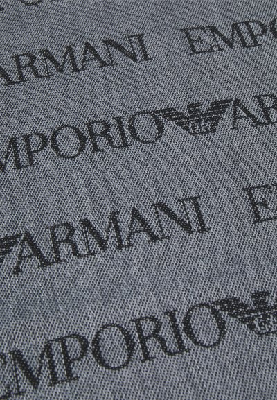 Denimstof med gentagne sorte bogstaver "Emporio Armani" og logo på en grå baggrund, der fremhæver en glat tekstur og sammenhængende design.