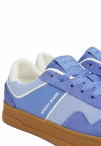 Blau und lila Freizeit-Sneaker mit weißem Rand, blauen Schnürsenkeln, "Tommy Jeans"-Logo an der Seite und brauner Gummisohle.
