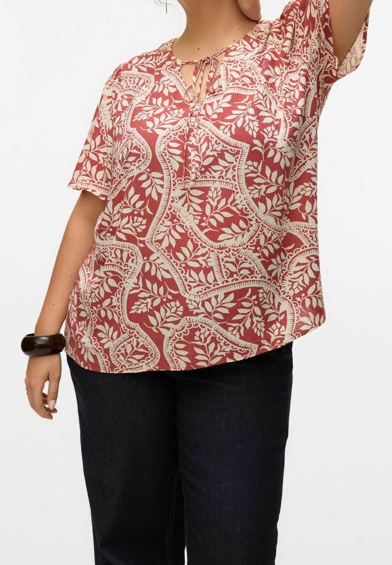 Blusa de textura suave con patrón rojo y beige, de mangas cortas, escote en forma de ojal y un ajuste relajado, que presenta motivos florales.