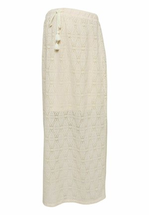 Jupe longue crème en crochet avec ceinture élastique et liens décoratifs à pompons, présentant un motif en losanges.